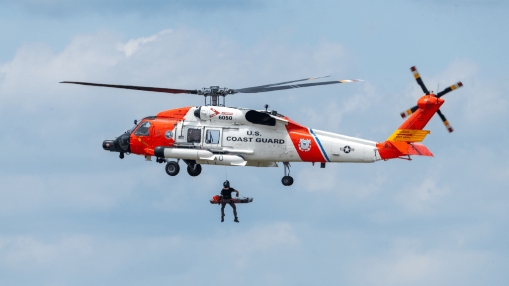 Image of a man being lowered out of a helicopter in the air